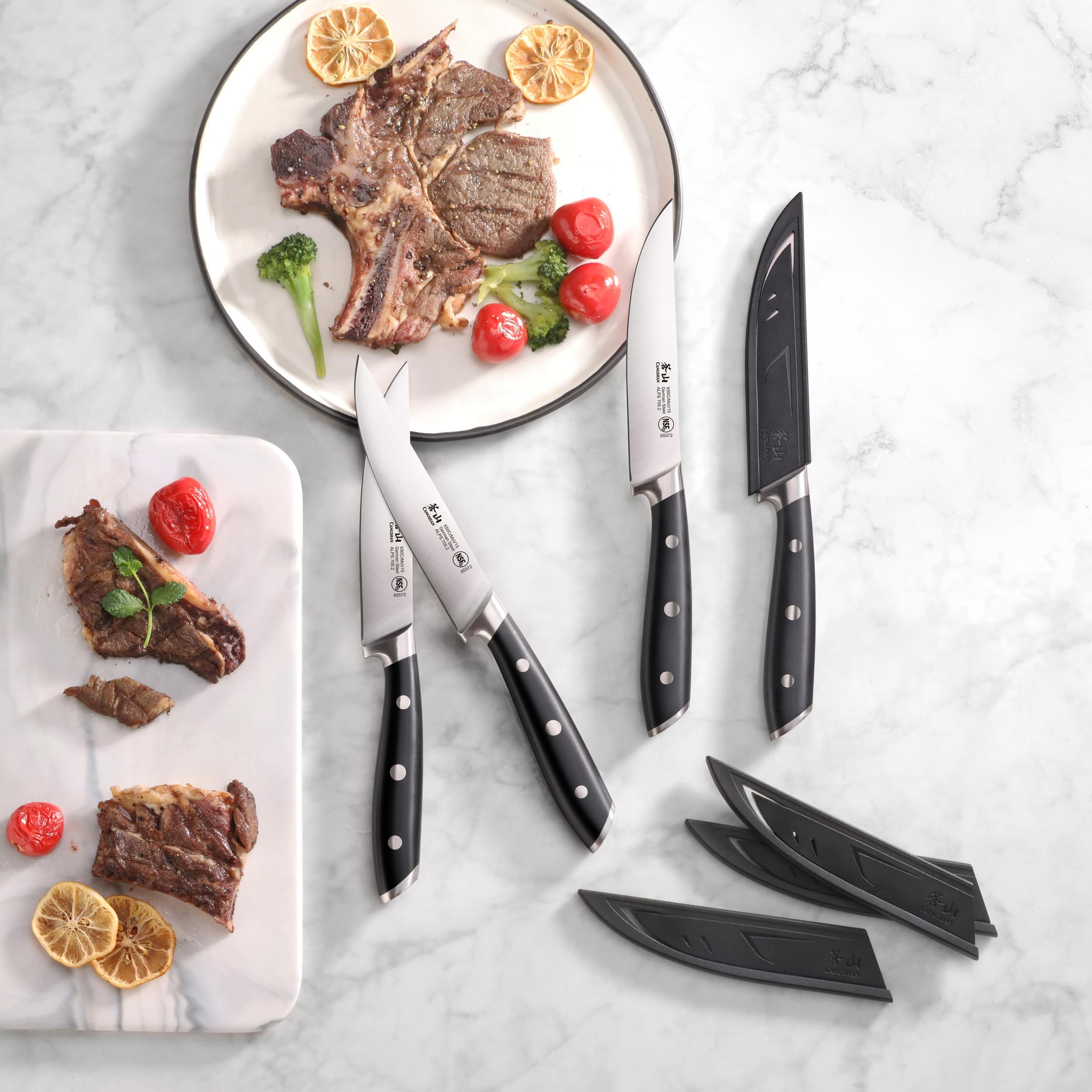 Cangshan professional knife set steel steak arranged on a marble surface next to a plate of grilled meat and roasted vegetables.