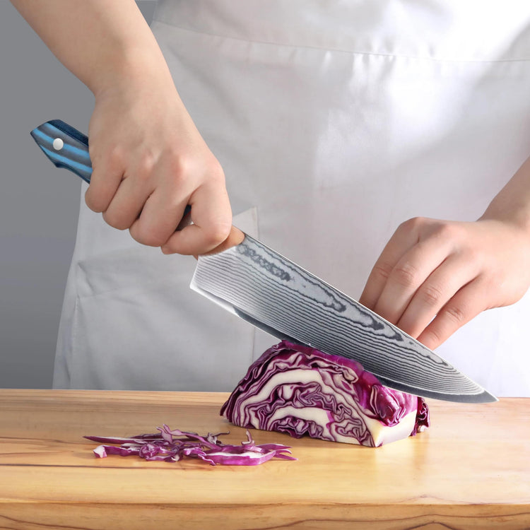 Hand holding a blue-handled knife slicing purple cabbage on a wooden cutting board.