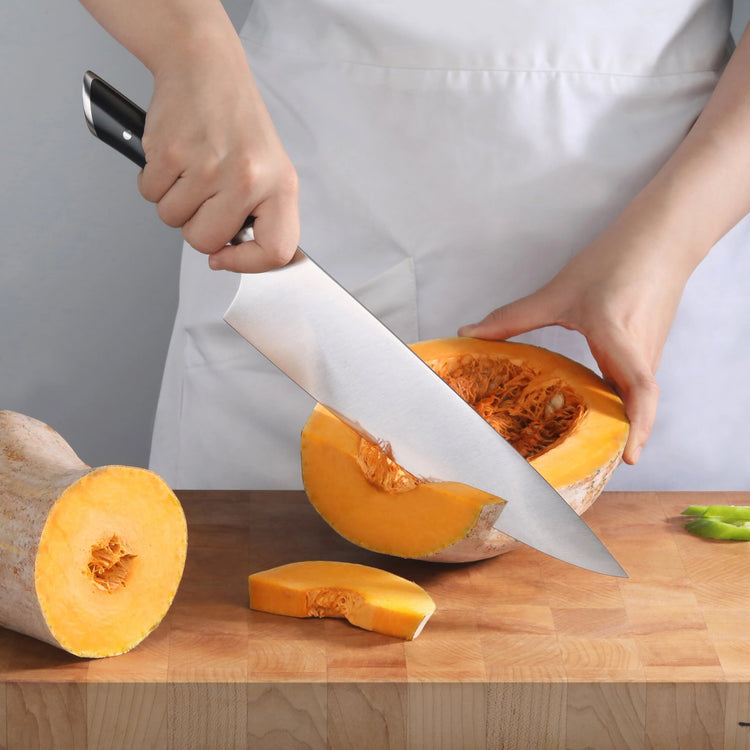 Person slicing a butternut squash on a wooden cutting board with a large chef's knife.
