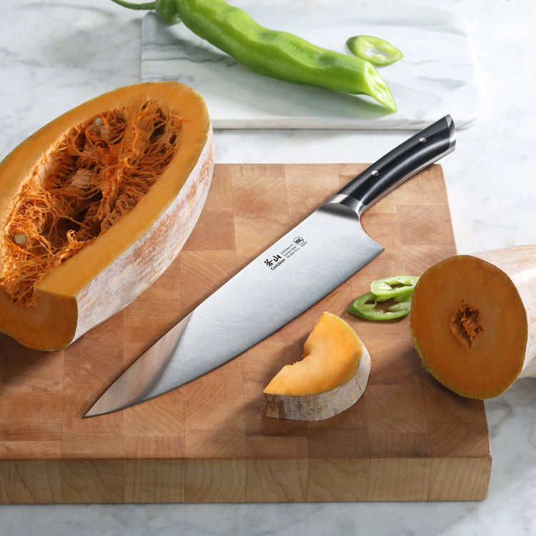10-inch chef's knife with black handle on wooden cutting board, sliced pumpkin and green chili nearby.