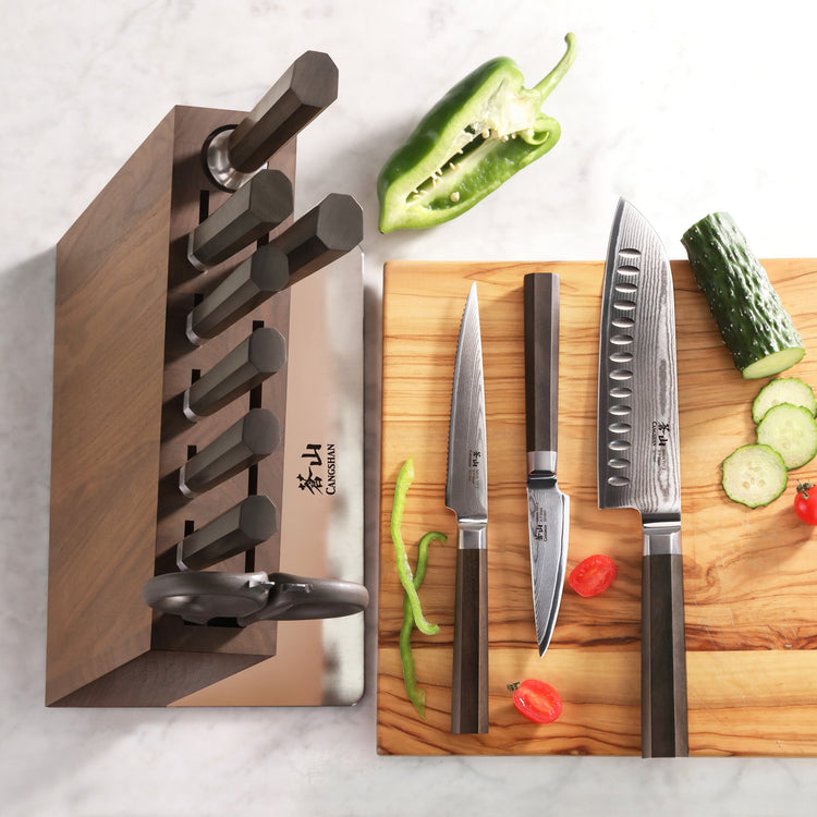 MAYA Series 12-piece knife block set with walnut block and Damascus steel kitchen knives on a cutting board.