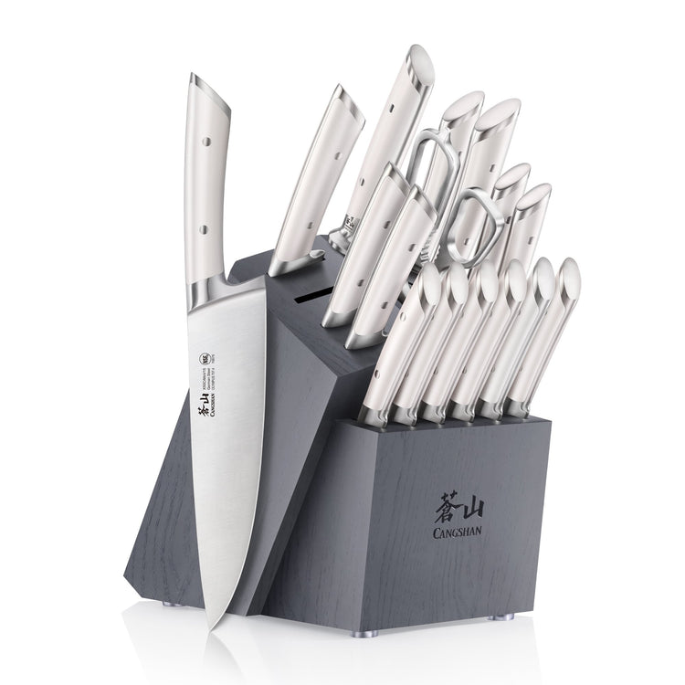 Black wooden knife block holding multiple stainless steel knives and kitchen scissors arranged in slots.