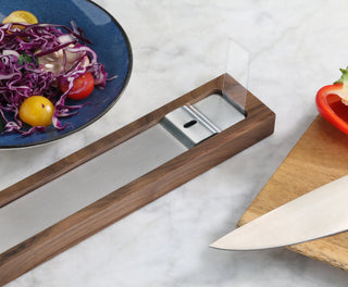 
                    
                      Walnut magnetic knife bar with metal strip on marble countertop next to cutting board, knife, and salad plate.
                    
                  