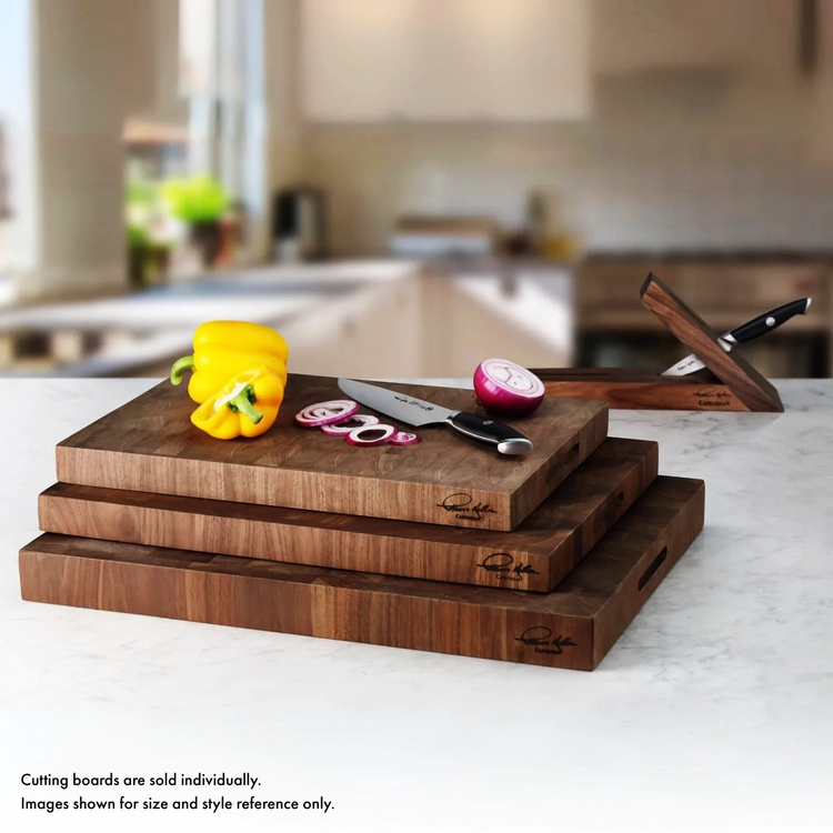 Stacked walnut end-grain cutting boards with a sliced red onion, yellow bell pepper, and a knife on a kitchen counter.