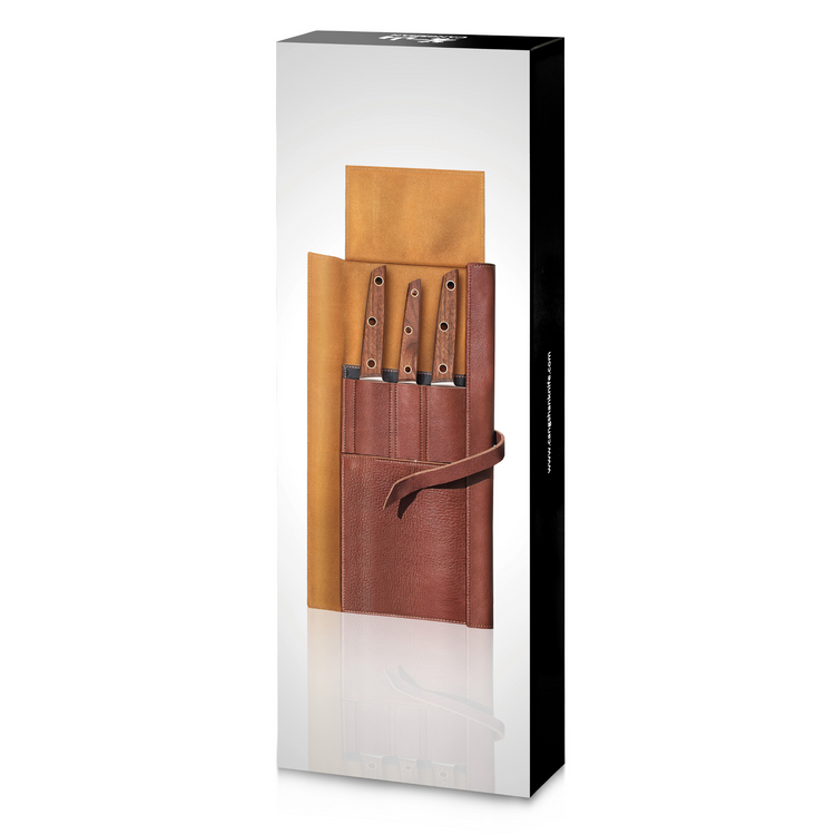 Four knives with wooden handles in a brown leather roll-up case, partially unrolled, inside a tall black and white box.