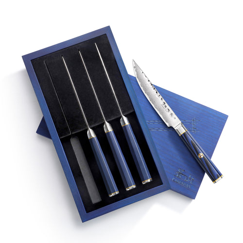 Four steak knives with blue handles and serrated blades in a blue presentation box, one knife outside the box.