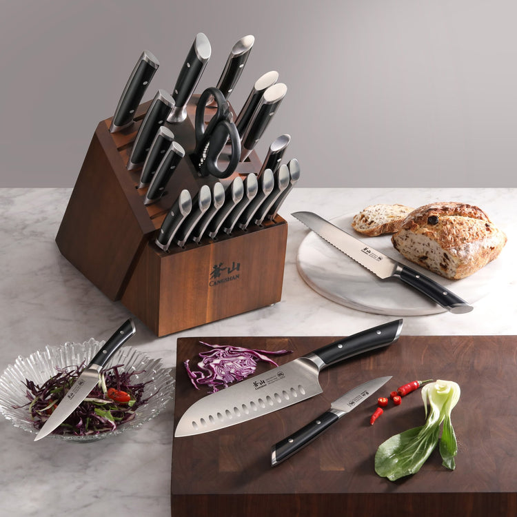 23-piece knife block set with various knives, kitchen scissors, and bread on a marble surface and cutting board.