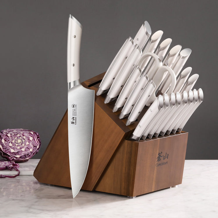 23-piece knife set with stainless steel knives in an acacia wood block on a marble surface.