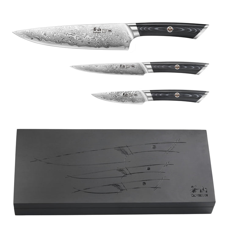 Three Damascus steel knives with patterned blades and black handles, displayed above a closed black wooden box with knife out