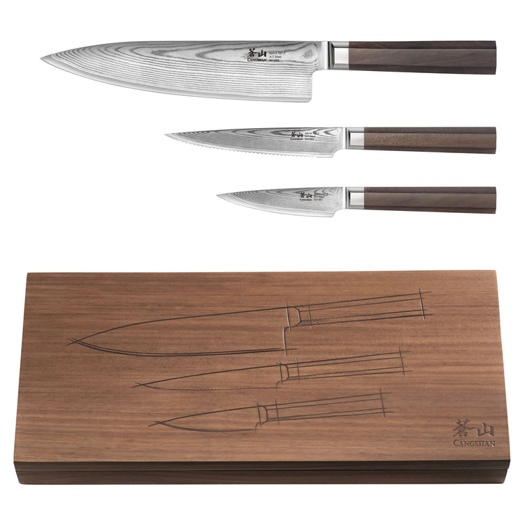 Three Damascus steel knives with wooden handles displayed above a walnut wood box with knife outlines engraved on the lid.