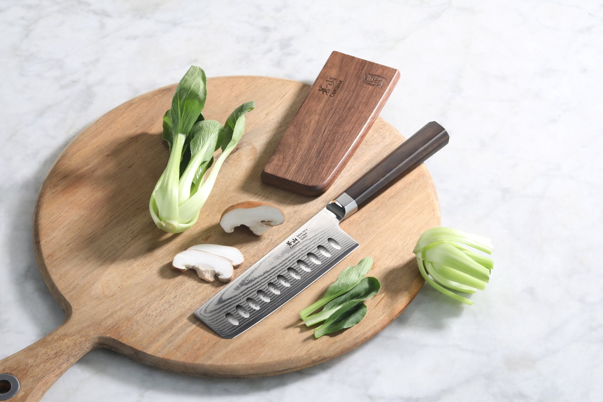 MAYA Series 5-Inch Nakiri Knife in X-7 Damascus Steel with a wooden sheath and vegetables on a cutting board.