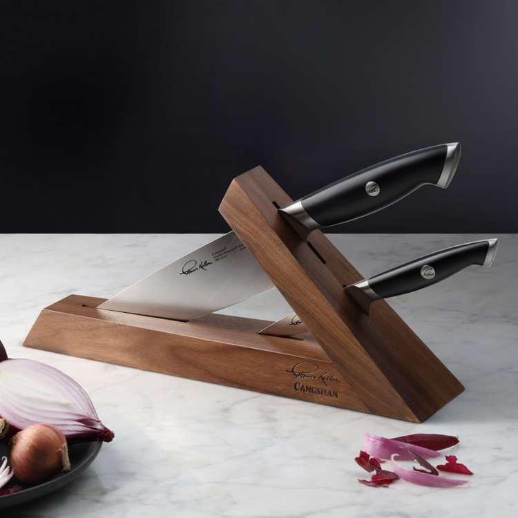 Wooden knife block holding two knives with black handles and stainless steel blades on a marble surface.