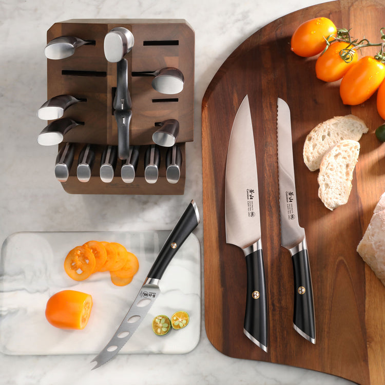 Knife block set with various knives in an acacia wood block, two knives on a cutting board, and sliced vegetables nearby.