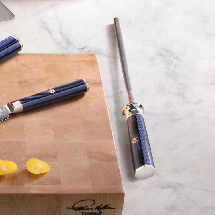 Blue-handled honing steel with a diamond-coated rod next to a wooden cutting board with a blue-handled knife and lemon wedges