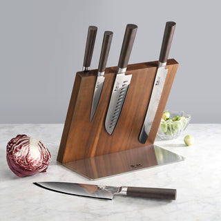 
                    
                      Six kitchen knives with dark handles in a wooden and metal magnetic block, with a cabbage and a bowl of Brussels sprouts near
                    
                  