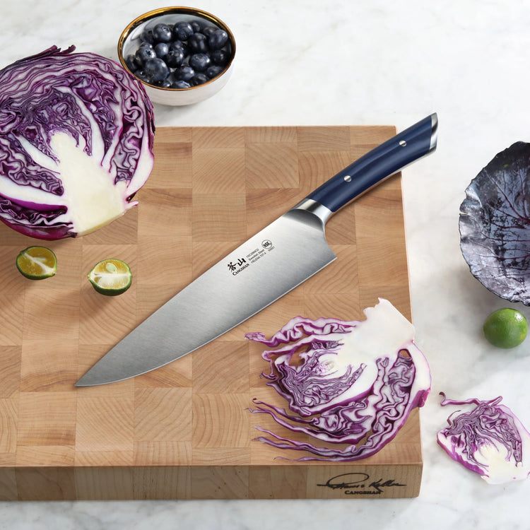8-inch chef's knife with navy blue handle on wooden cutting board, surrounded by sliced purple cabbage, lime, and blueberries