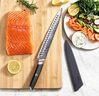 
                    
                      AIRA Series 10-Inch Carving Knife with 135-Layer Damax™ Steel beside a salmon fillet and salad on a cutting board.
                    
                  