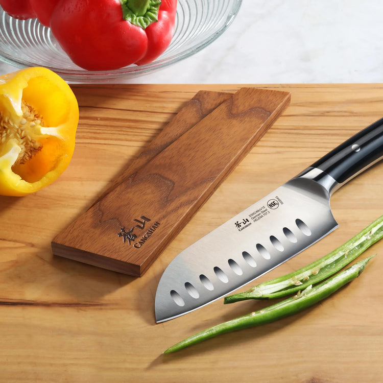 Ash wood magnetic knife sheath next to a Santoku knife and green beans on a wooden cutting board.