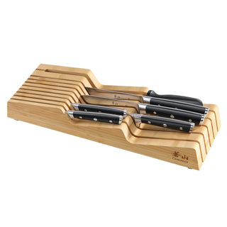 
                    
                      Seven kitchen knives with black handles arranged in a wooden in-drawer knife block with slots.
                    
                  