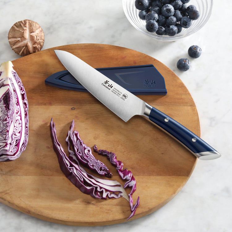 5.5-inch utility knife with blue handle on wooden cutting board, sliced purple cabbage, mushroom, and bowl of blueberries nea