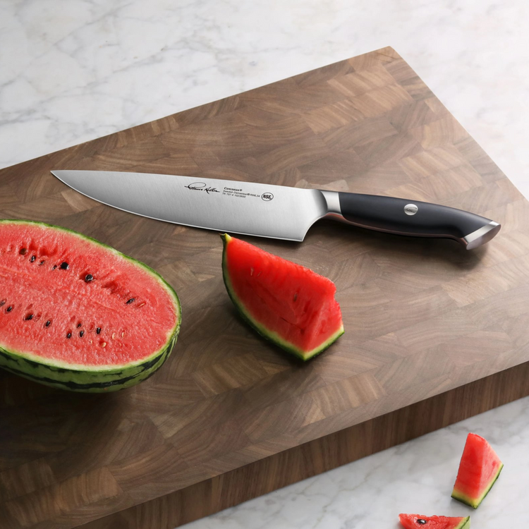 TKSC 8-inch chef's knife with black handle on wooden cutting board next to sliced watermelon pieces.