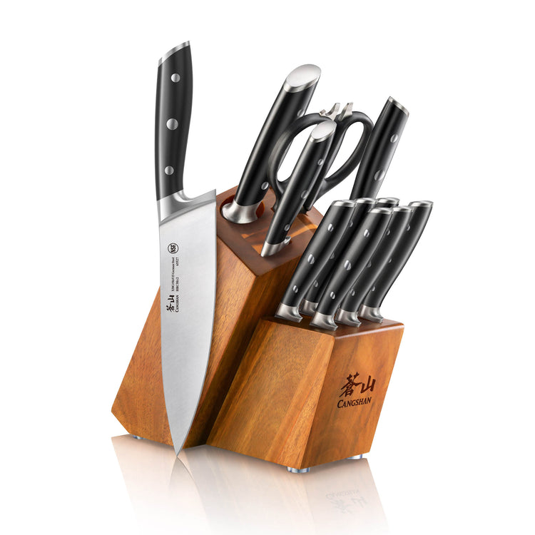 Wooden knife block holding six knives, kitchen shears, and a sharpening rod with black handles and metal rivets.