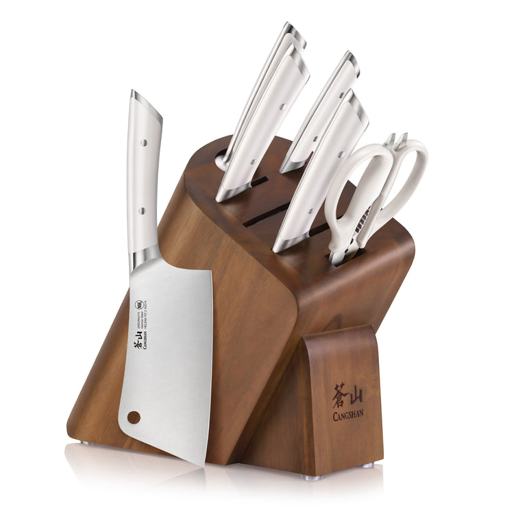 Wooden knife block holding five stainless steel knives and a pair of kitchen scissors.