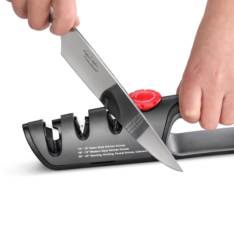 Hand sharpening a kitchen knife using a black three-slot adjustable knife sharpener with a red dial.