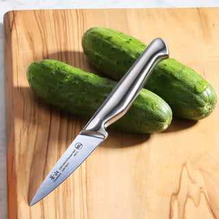 
                    
                      Stainless steel knife with ergonomic handle resting on two whole cucumbers on a wooden cutting board.
                    
                  