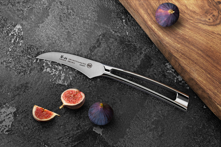 2.75-inch peeling knife with curved blade and ergonomic handle on dark surface with figs and wooden board.