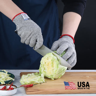 
                    
                      Hands wearing gray cut resistant gloves slicing a head of cabbage on a wooden cutting board.
                    
                  