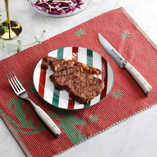 
                    
                      Grilled steak on striped plate with steak fork and serrated knife on red placemat.
                    
                  