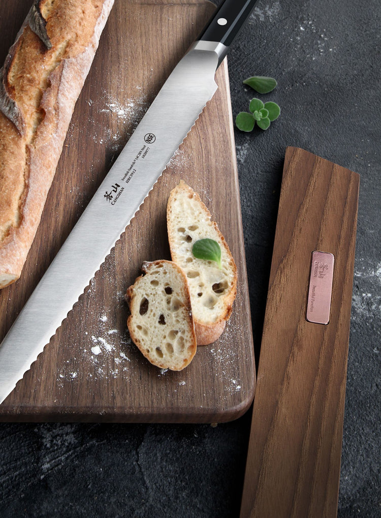 Serrated bread knife on wooden cutting board with sliced bread and solid ash wood magnetic knife sheath nearby.