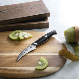 
                    
                      Small curved peeling knife with black handle on wooden cutting board next to sliced kiwi and kiwi peel.
                    
                  