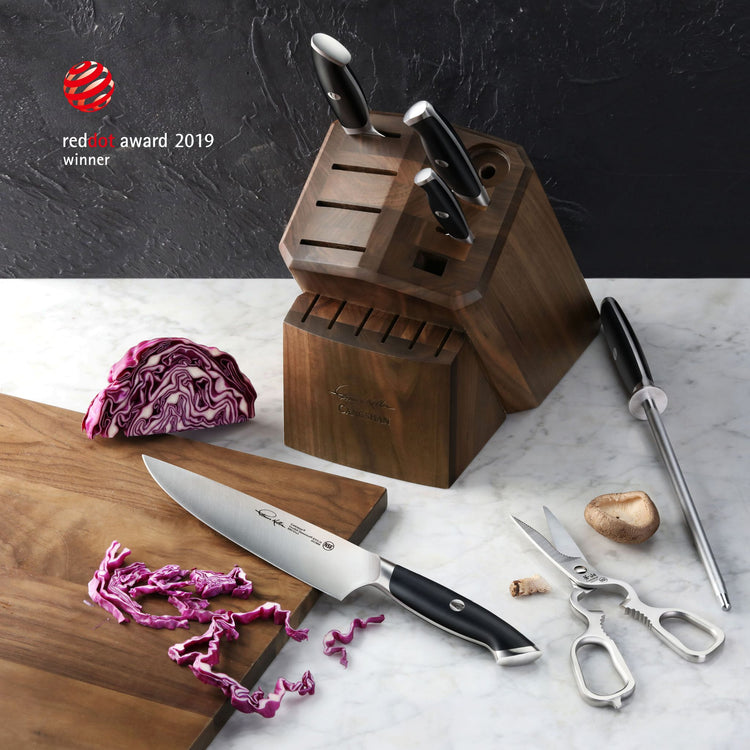 Wooden knife block with three knives inserted, one chef knife on cutting board with sliced red cabbage, kitchen scissors, and