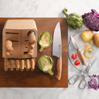 
                    
                      Wooden knife block with knives, a cutting board, halved artichokes, peeled potatoes, cherry tomatoes, scissors, and purple ca
                    
                  