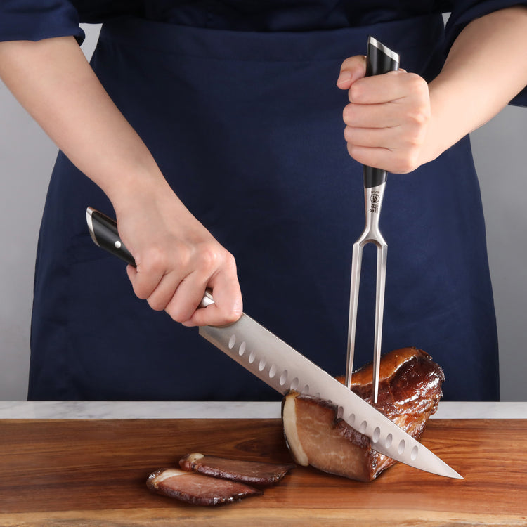 Person carving a cooked meat roast on a wooden cutting board using a carving knife and fork with black handles.