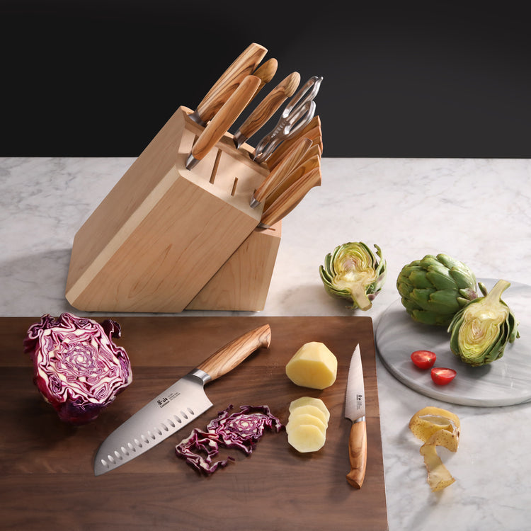 15-piece knife set with wooden block, knives with wooden handles, cutting board with sliced vegetables and peeled potato.