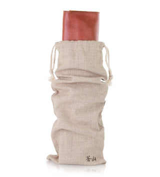 
                    
                      Beige drawstring fabric bag holding a rolled-up brown leather knife roll case.
                    
                  