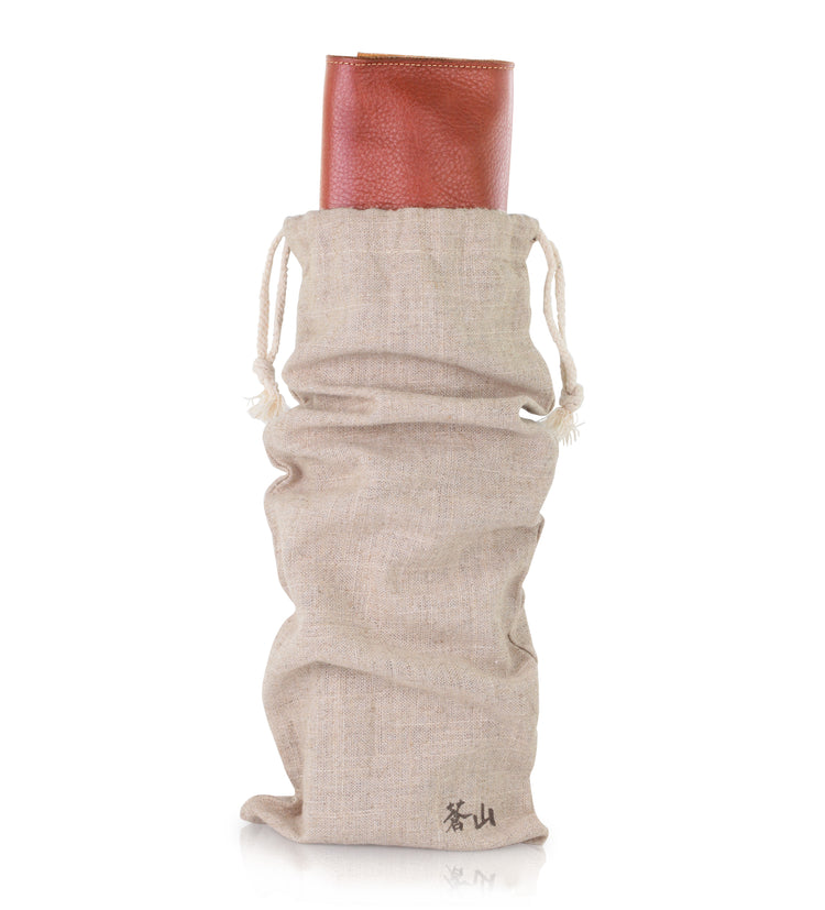 Beige drawstring fabric bag holding a rolled-up brown leather knife roll case.