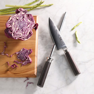 
                    
                      6-inch chef's knife and sharpening steel crossed on marble surface next to wooden board with halved red cabbage and asparagus
                    
                  