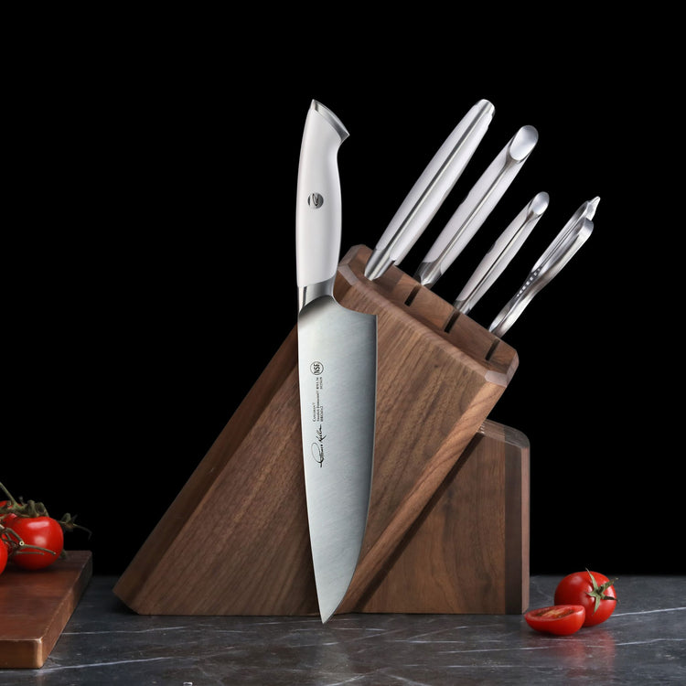 Wooden knife block holding five stainless steel knives with white handles, arranged on a dark countertop.
